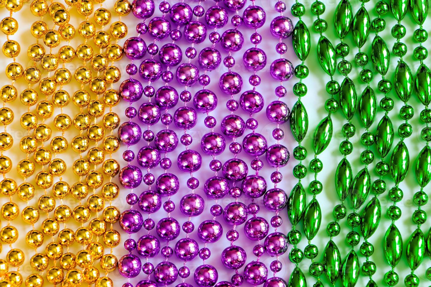 Mardi Gras background. Multi-colored beads close-up. Festive decorations in gold, green and purple colors. Fat Tuesday symbol. photo