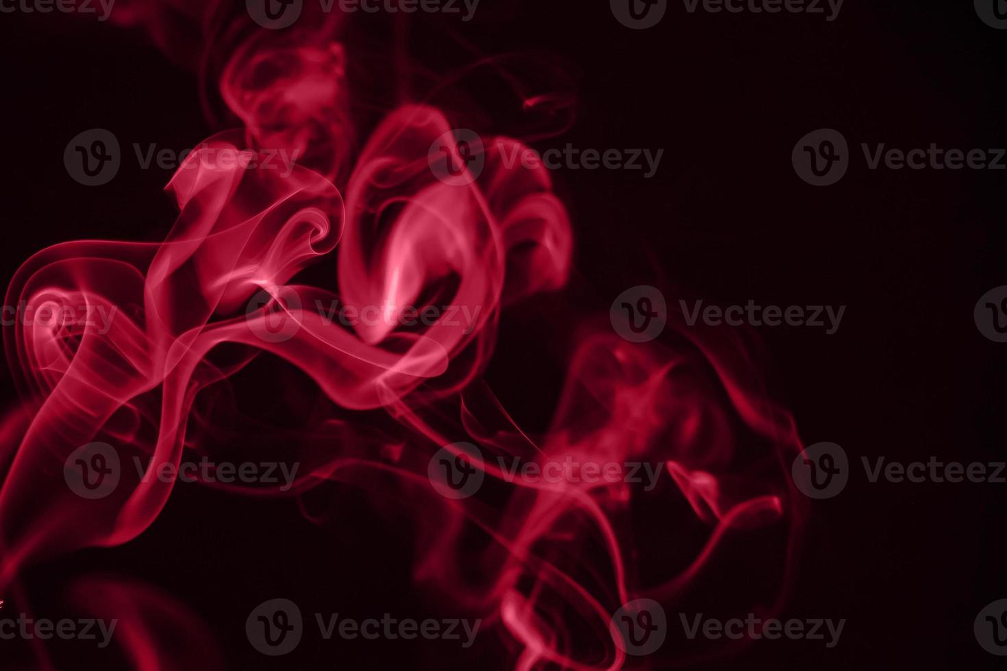 Red puffs of smoke on black background. Color of the year 2023 - Viva Magenta photo