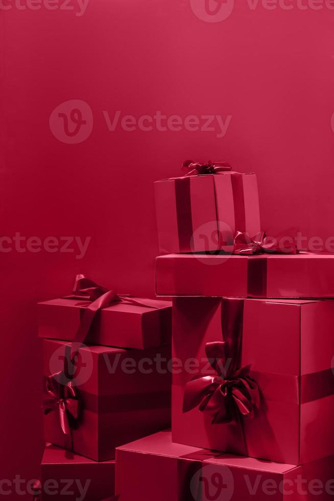 Gift boxes with bow on red background. Color of the year 2023 - Viva