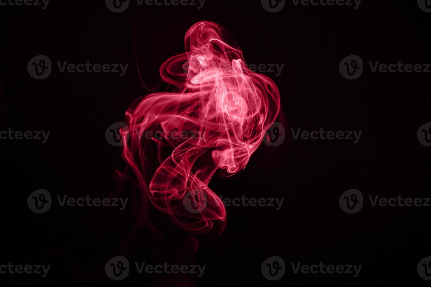 Unusual red smoke on black background. Color of the year 2023 - Viva Magenta photo