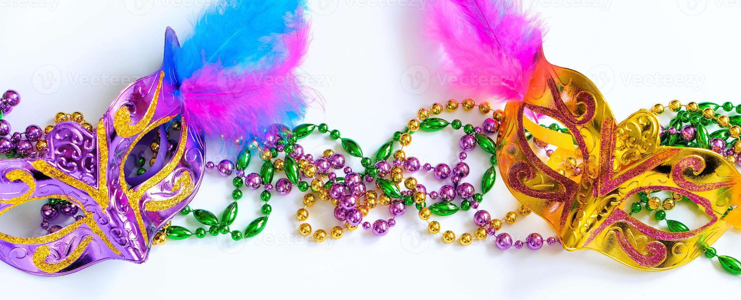 Two carnival masks with feathers and multi-colored beads on white background. Mardi Gras or Fat Tuesday symbol. photo