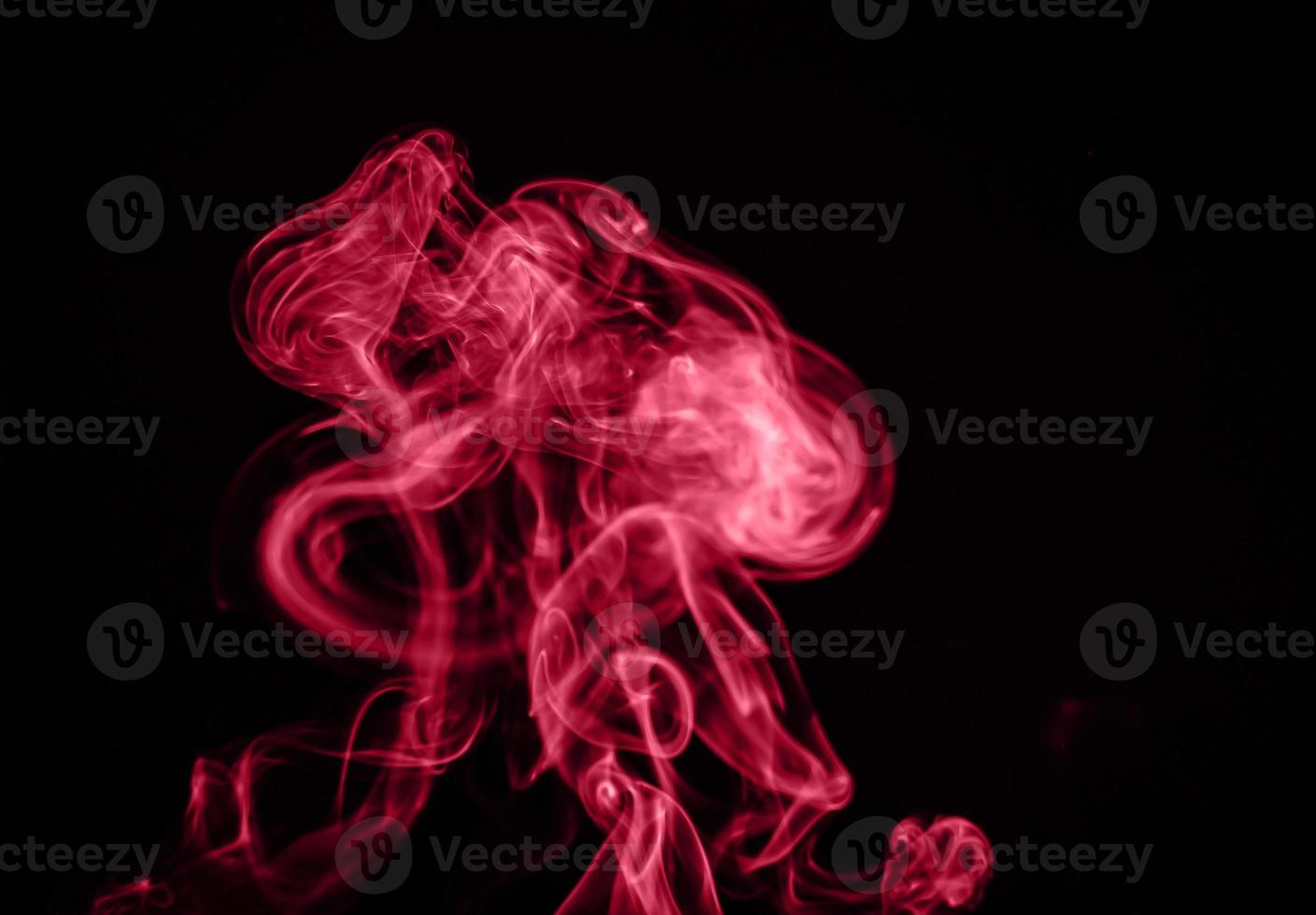 Unusual red smoke on black background. Color of the year 2023 - Viva Magenta photo