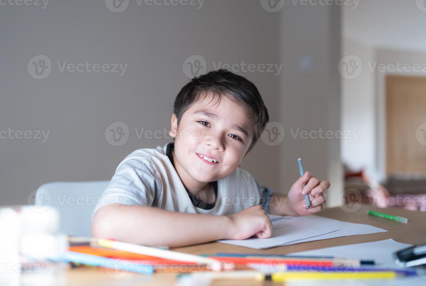 concepto de educación, niño de la escuela que usa dibujos de pluma de color gris o bocetos en papel, niño de retrato sentado en la mesa haciendo la tarea en la sala de estar, niño disfruta de la actividad artística y artesanal en casa el fin de semana foto