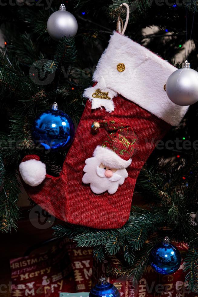 Christmas stocking. Red sock with snowflakes for Santa's gifts hanging on the Christmas tree. Winter holidays photo