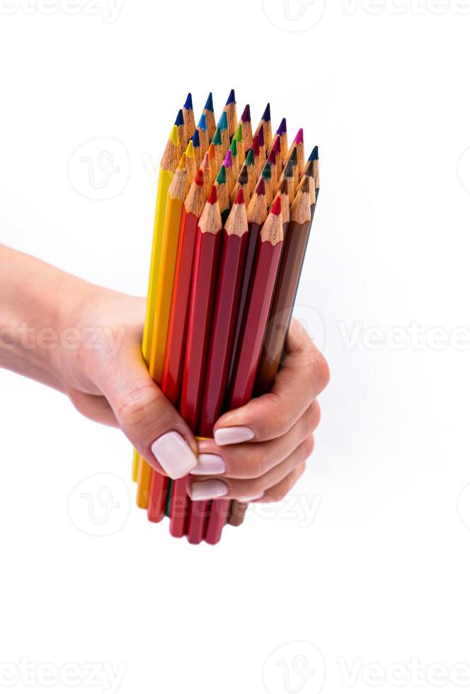 lápices multicolores para dibujar en una mano femenina. lápices multicolores en mano femenina sobre fondo blanco, primer plano, espacio de copia, arte moderno. diseño moderno foto