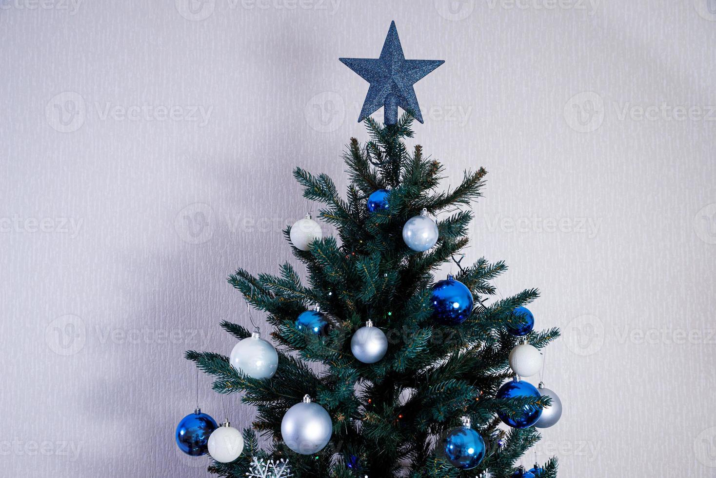 christmas tree with colorful balls and gift boxes over white brick wall with blue and white balls photo