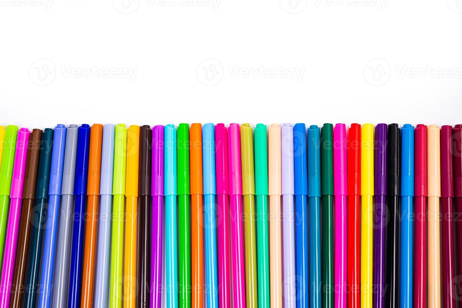 A set of multi-colored felt-tip pens in a row, rainbow on a light white banner background. Drawing markers, pencils, ink, artist tools, creativity, leisure, hobby. Colorful school supplies. photo