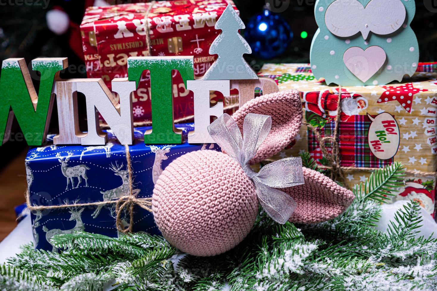 The inscription winter from a tree on a New Year's. On the spruce branches against the background of a snow cover are New Year's blue, white balls with spruce cones and a box with a gift. Christmas photo