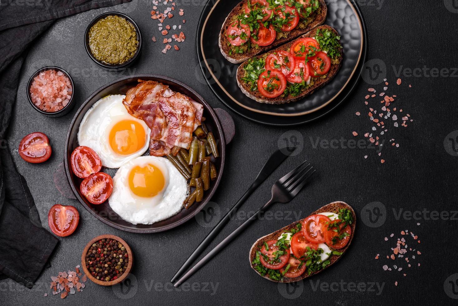 Tasty breakfast consists of eggs, bacon, beans, tomatoes, with spices and herbs photo