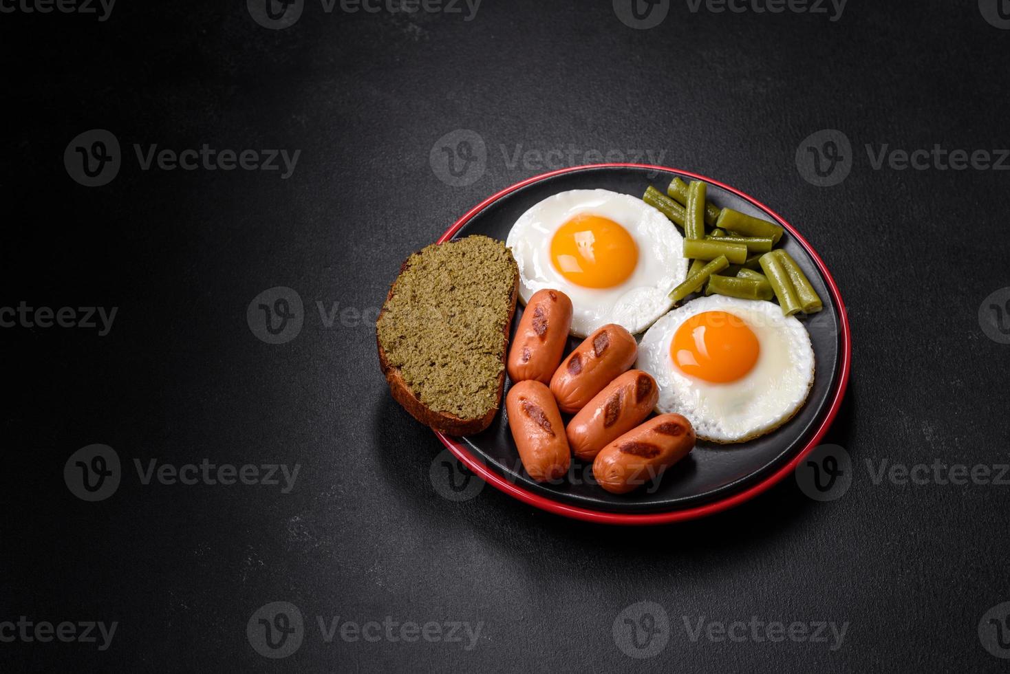 Tasty English breakfast of fried eggs, beans, asparagus, sausages with spices and herbs photo