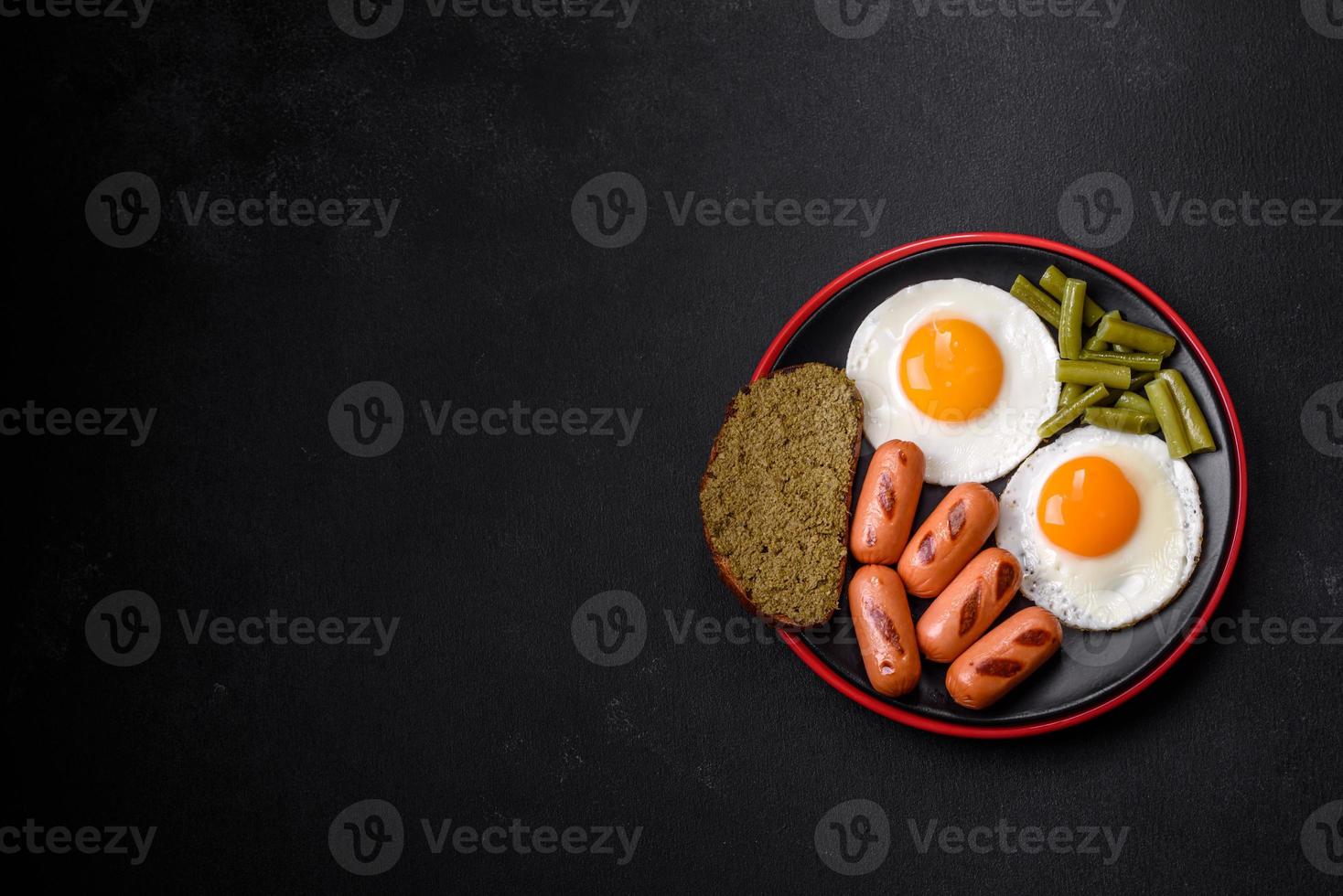 Tasty English breakfast of fried eggs, beans, asparagus, sausages with spices and herbs photo