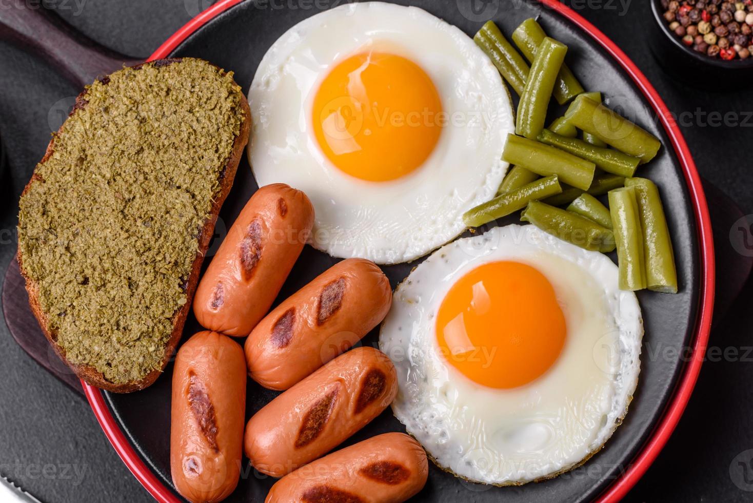 sabroso desayuno inglés de huevos fritos, frijoles, espárragos, salchichas con especias y hierbas foto