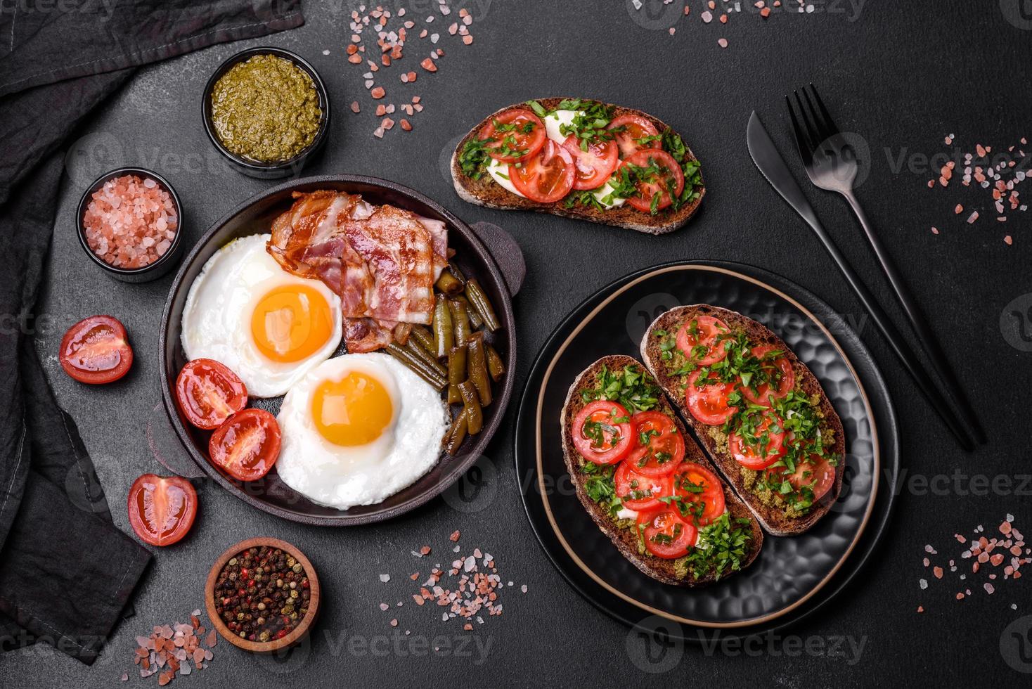 Tasty breakfast consists of eggs, bacon, beans, tomatoes, with spices and herbs photo