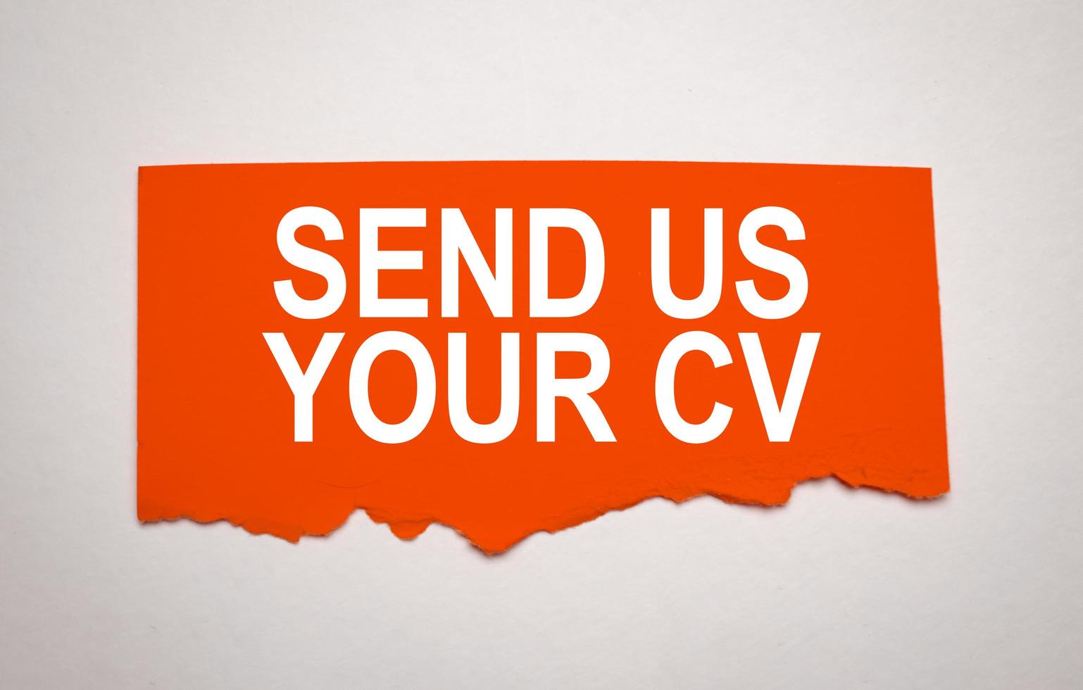 send us your cv on torn red paper on grey background photo