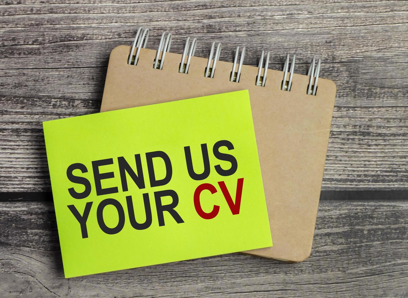 send us your cv. Text on green business card with pen photo