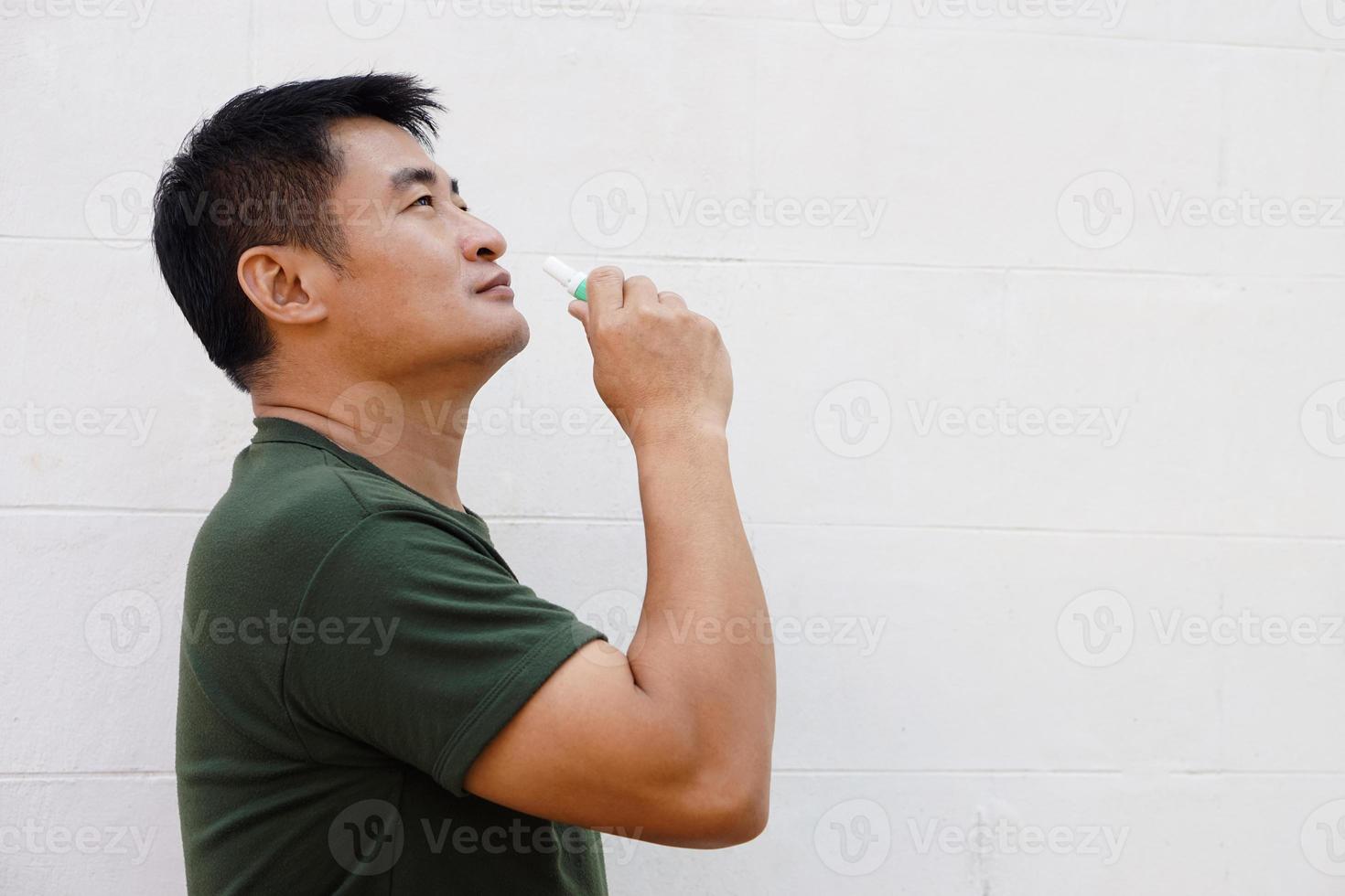 Asian man uses inhaler to smell  for relieve dizzy and faint symptoms. Concept , health problem, sickness and remedy. Increases freshness, reduces dizziness and stuffy nose. self take care. photo