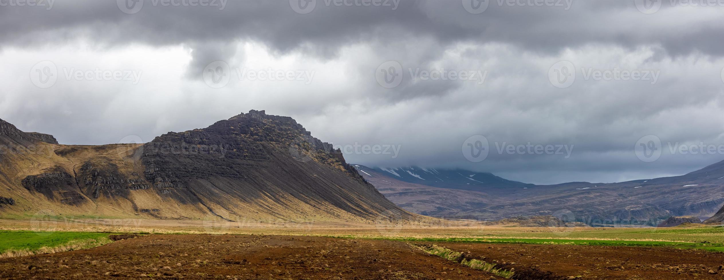 vista panorámica del paisaje montañoso con nubes oscuras en el campo de islandia. foto
