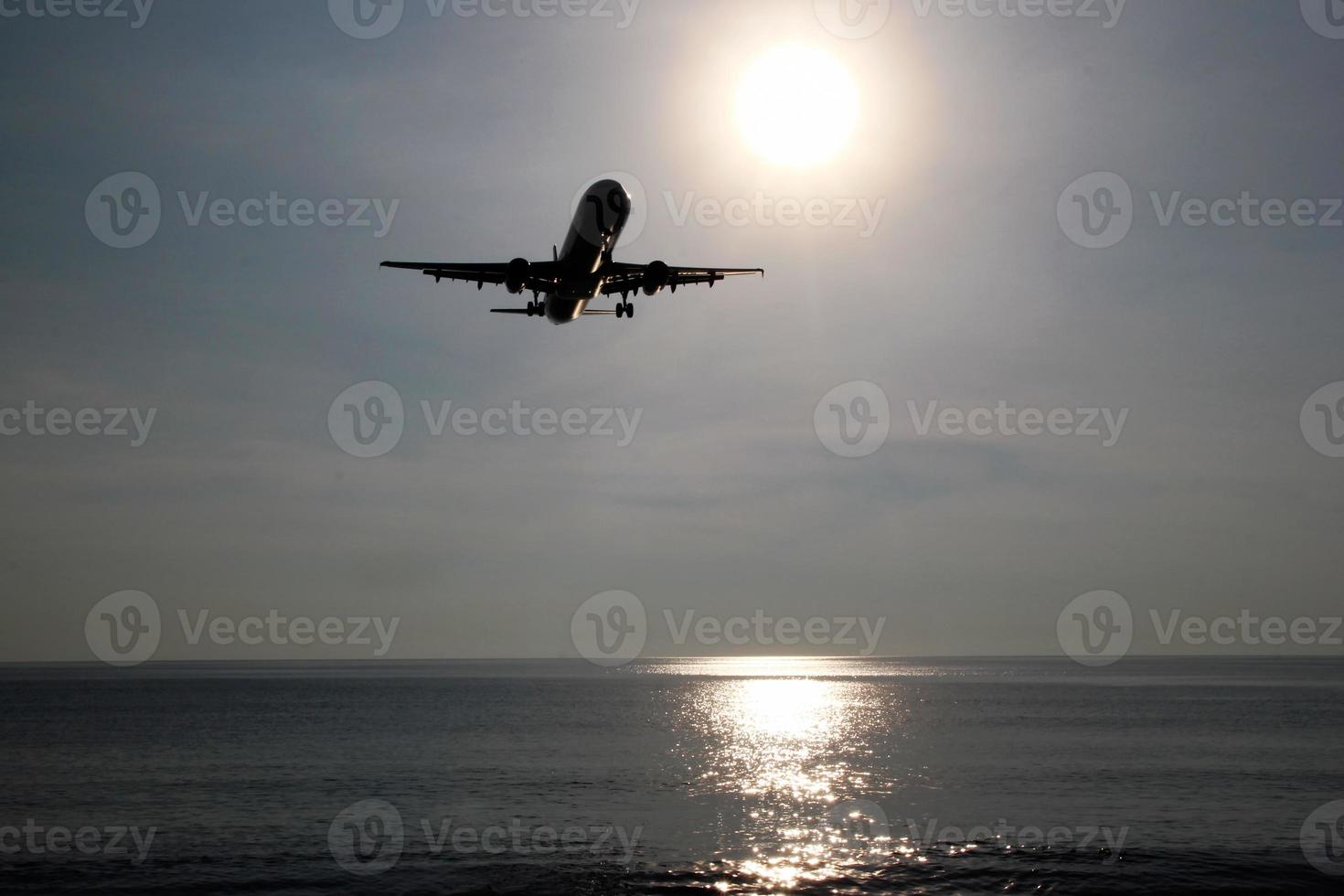 The view on a sea with plane in a sky in a sunny weather. Phuket, Thailand. photo