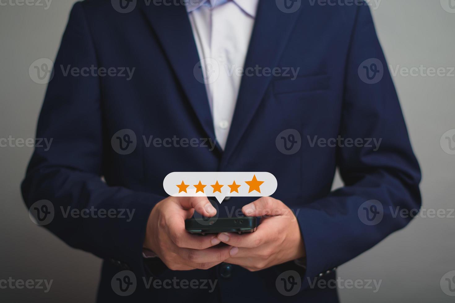 close up on customer man hand pressing on smartphone screen with gold five star rating feedback icon and press level excellent rank for giving best score point to review the service , business concept photo