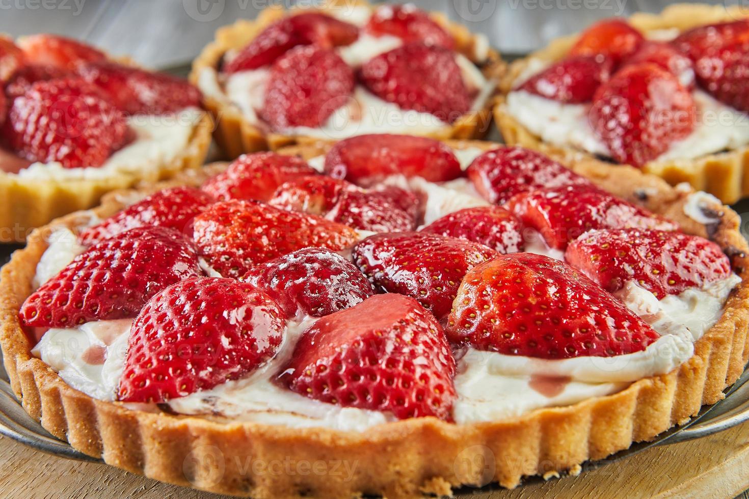 Round cream pie with strawberries. One big and three small photo