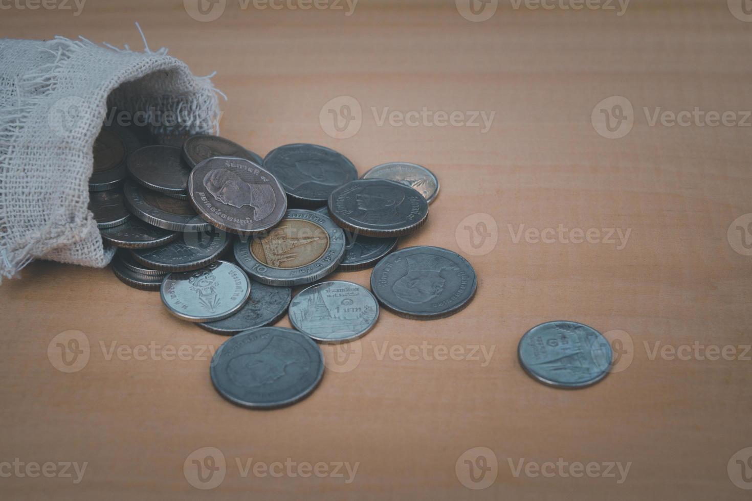 Close up of money bag pour the coin on the wooden table background photo