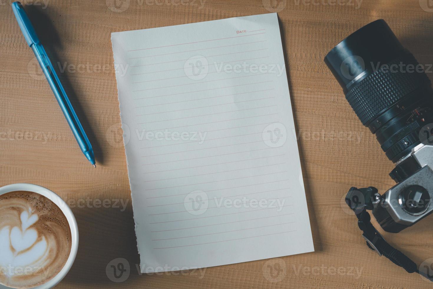 Top view of empty paper, coffee cup, camera and pen on the wooden table photo