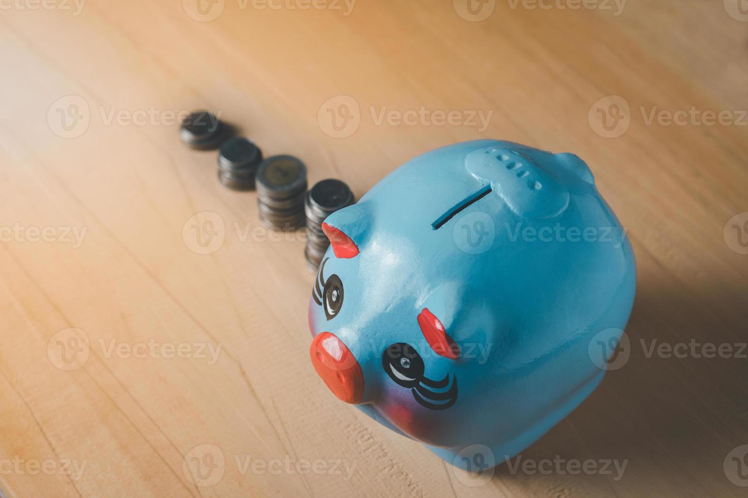 Bird eye view of blue piggy bank and coin orange light on the wooden table background photo