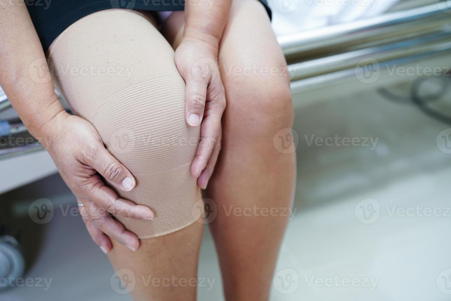 Asian senior woman wearing elastic support knee brace for reduce pain. photo