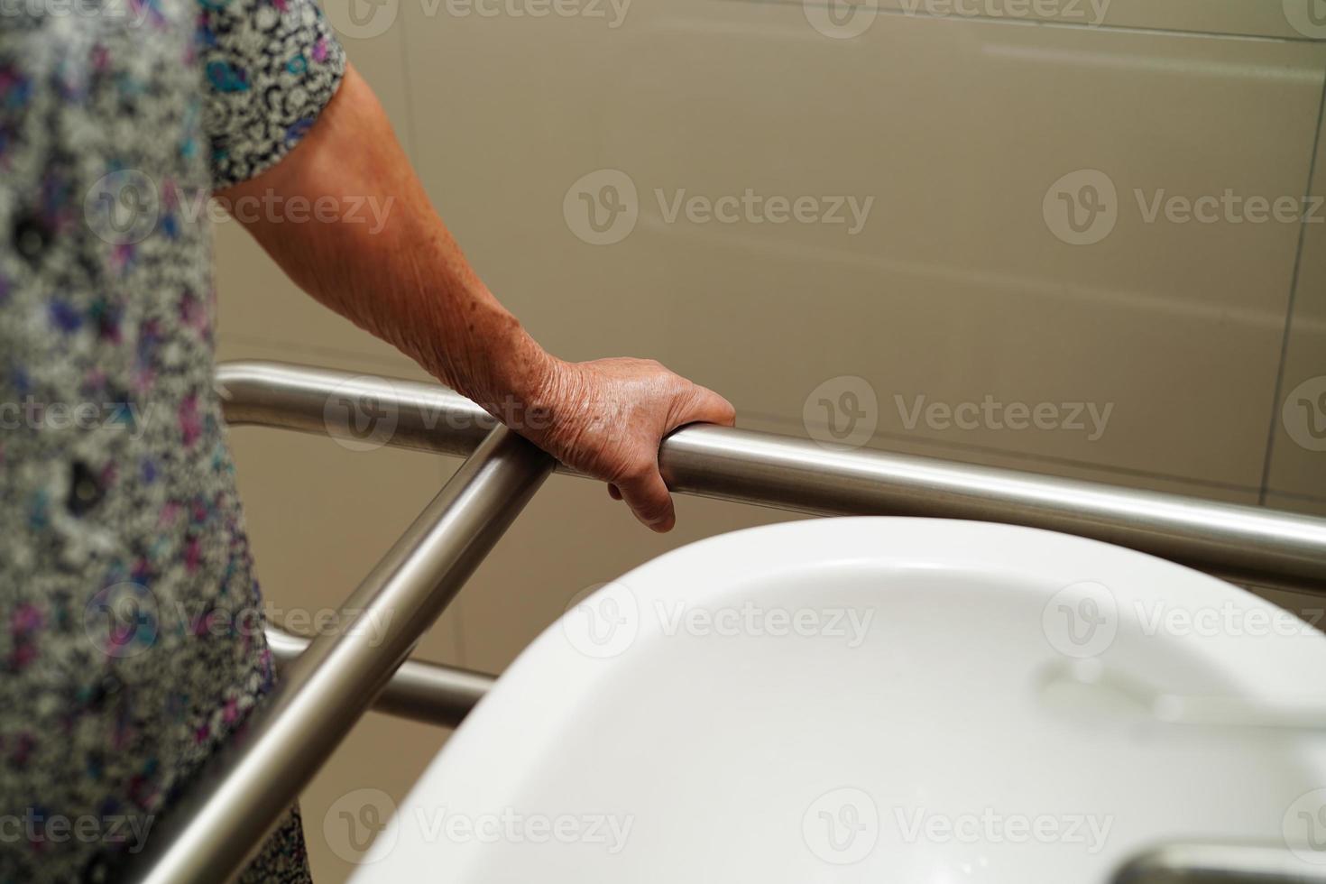 Asian elderly old woman patient use toilet support rail in bathroom