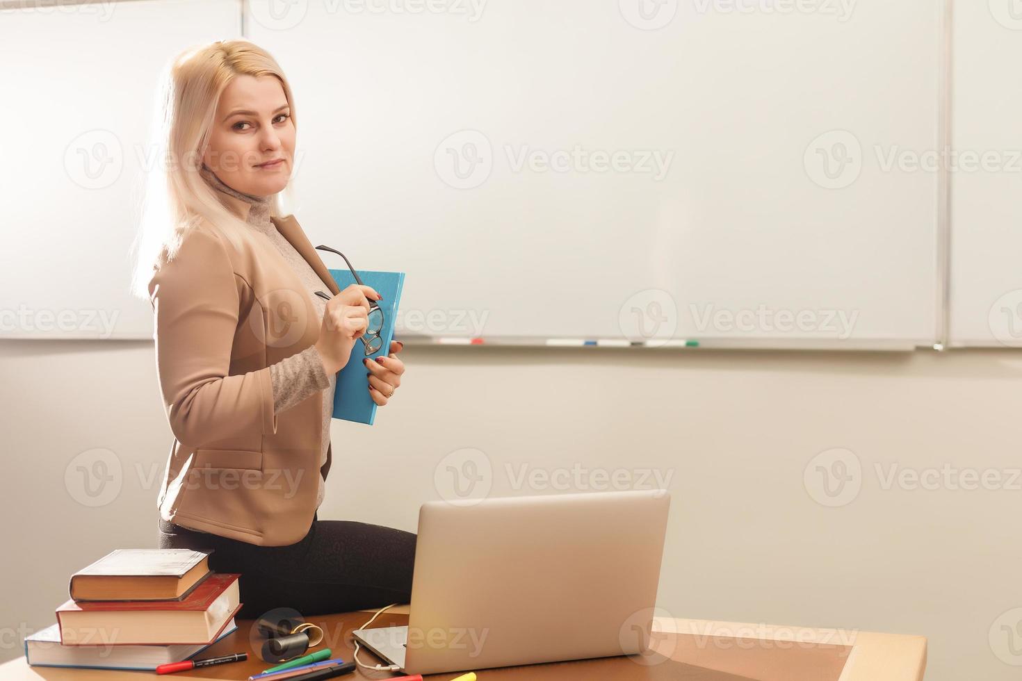 concepto de aprendizaje electrónico con un estudiante que sostiene su computadora portátil moderna, el tutor debe ser entusiasta y debe gustarle su materia, el maestro dibuja en el aula de la escuela, foto