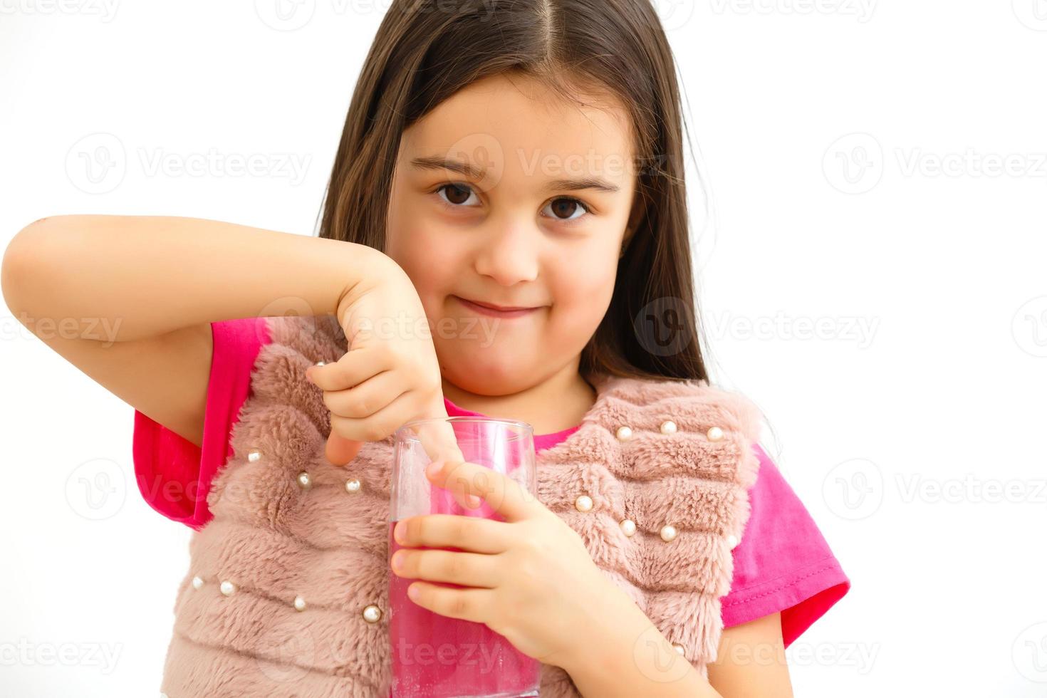 Smiling little girl with a glass of water on a white background photo