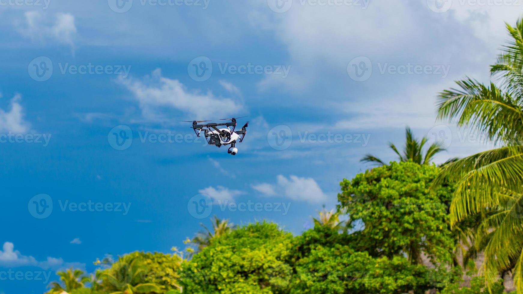 cuadricóptero de drones profesional con cámara digital en playa tropical. tomar imágenes de la ubicación de la luna de miel y el contenido de las vacaciones turísticas. tecnología digital para lugares especiales foto