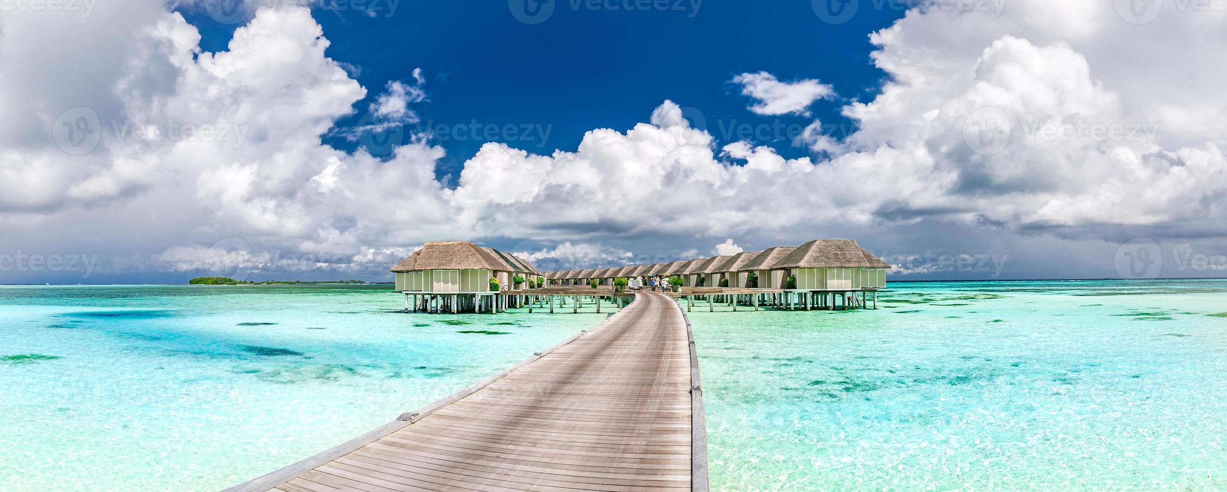 Maldives island beach panorama. Luxury water villas long wooden pier pathway. Tropical vacation and summer holiday background concept. Amazing scenery with copy space photo