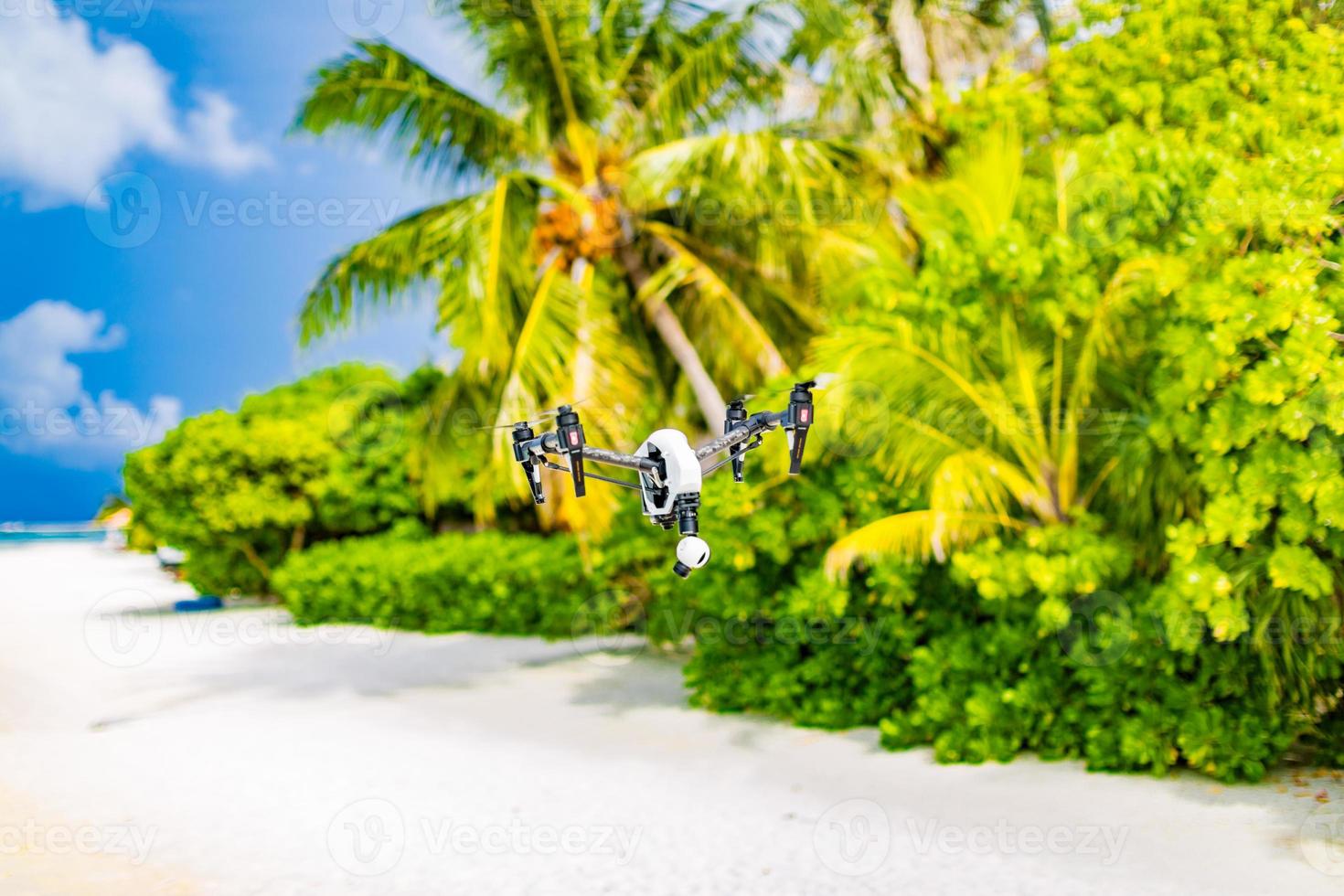 Professional drone quadcopter with digital camera on tropical beach. Taking footage of honeymoon location and tourist vacation content. Digital technology for special locations photo