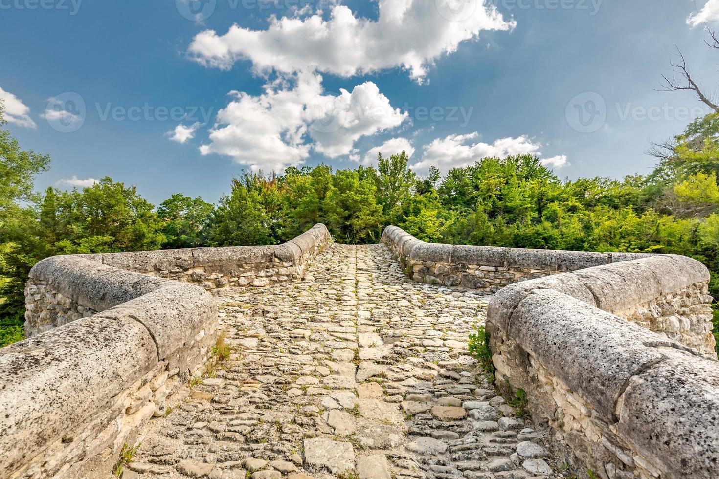 puente de piedra de roca a través de un pequeño estanque con árboles verdes bajo un cielo azul. paisaje histórico, idilio foto