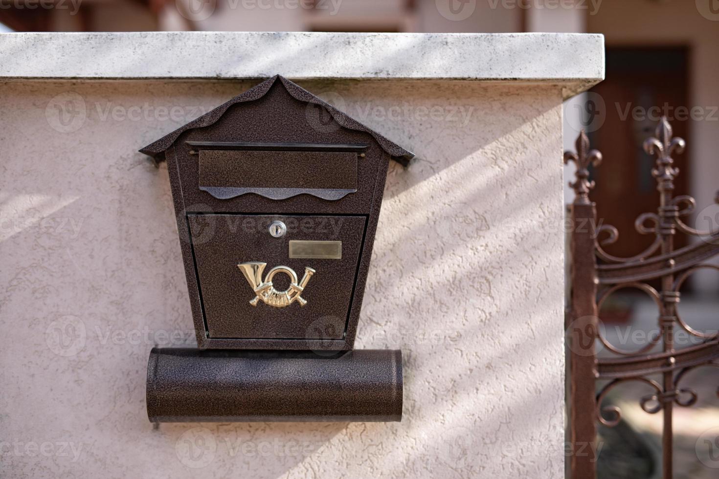 Old steel, iron mail box on stone brick wall, next to wooden fence on building or house door. Home related object, mail box photo