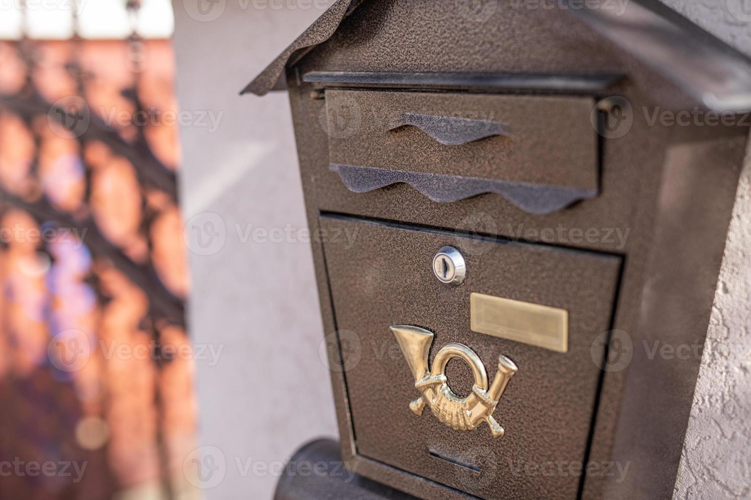 acero antiguo, buzón de correo de hierro en una pared de ladrillos de piedra, junto a una valla de madera en el edificio o en la puerta de la casa. objeto relacionado con el hogar, buzón de correo foto