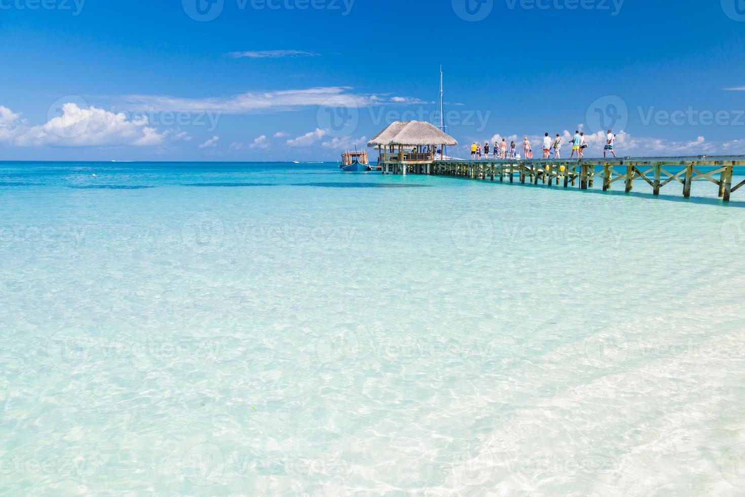 Maldives island beach, people going for adventure exotic travel destination. Wooden pier water villa, soft waves and calm sea, surf, adventure. Amazing landscape of tropical beach, vacation or holiday photo