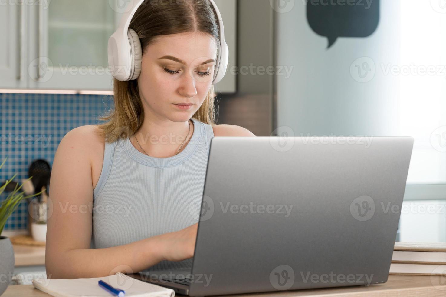 Closeup of a female in headphones working on laptop.Student writing lecture or woman works from home photo