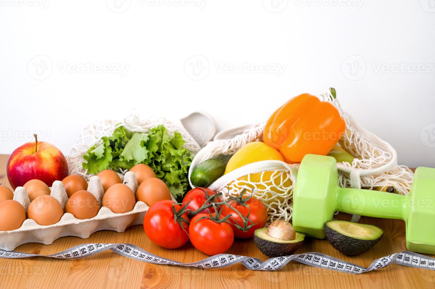 Vegetables anf fruit near dumbbells and measuring tape. Sport and diet cocnept. HEalthy eating habits photo
