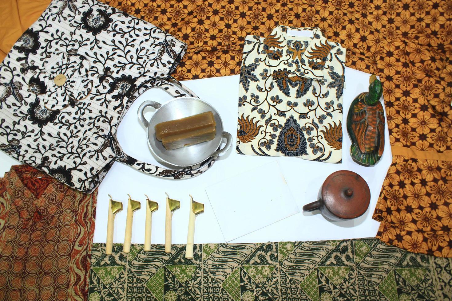 flat lay batik clotes with canting, small pan and wax earthenware glass isolated on white background photo