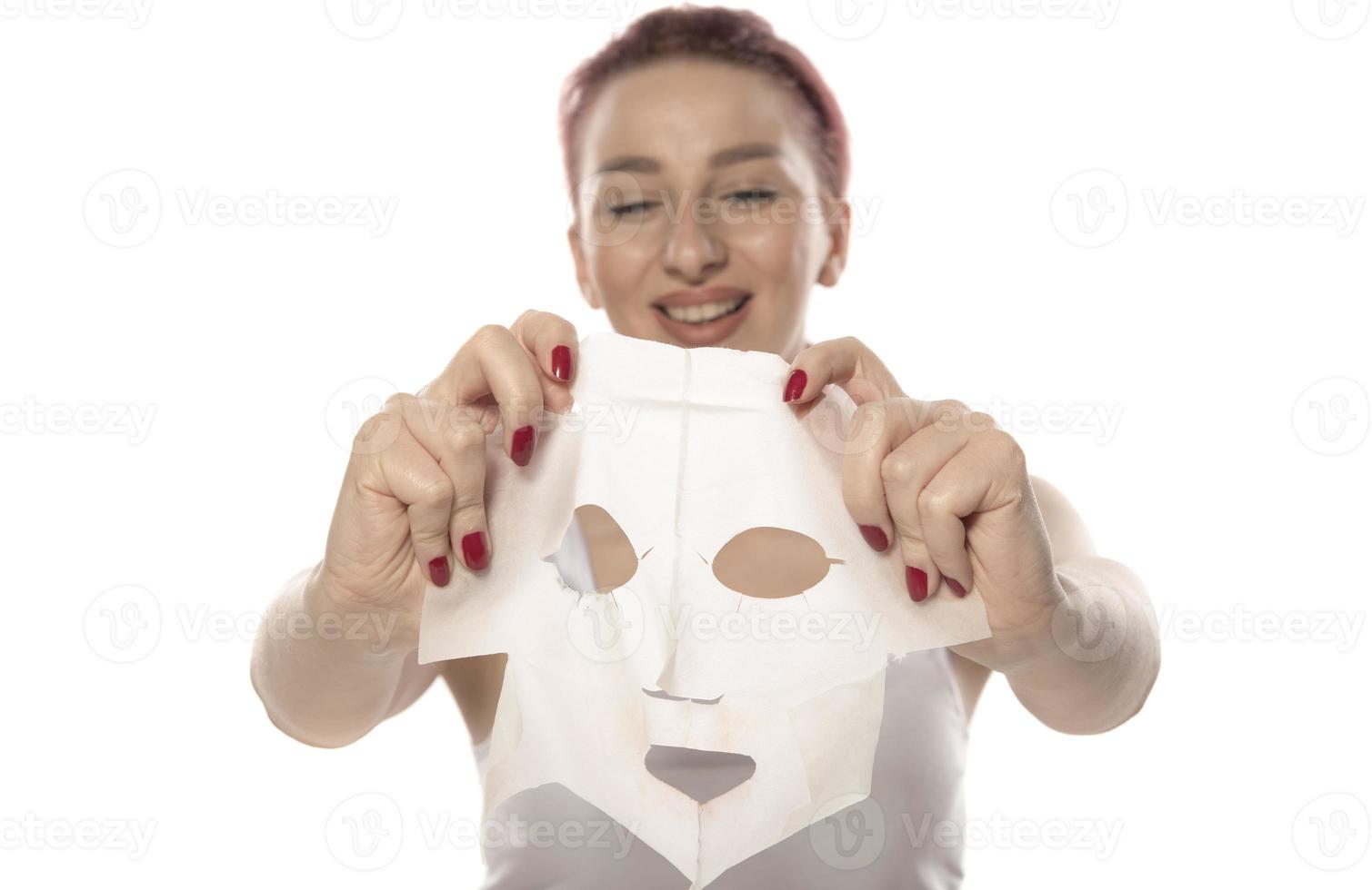 Face care and beauty treatments. Woman with a sheet moisturizing mask on her face isolated on white background photo