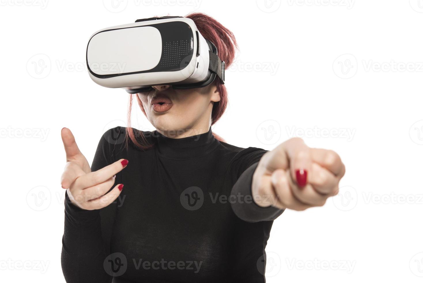 Pretty cute excited female in VR headset looking up and trying to touch objects in virtual reality photo