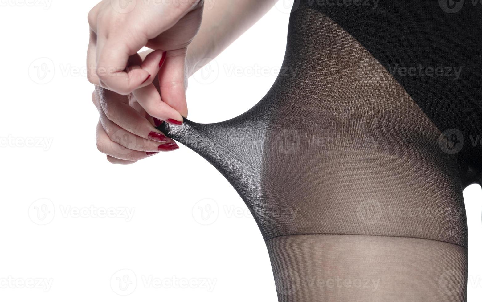 Woman puts on stockings on her beautiful long legs, isolated on white background photo