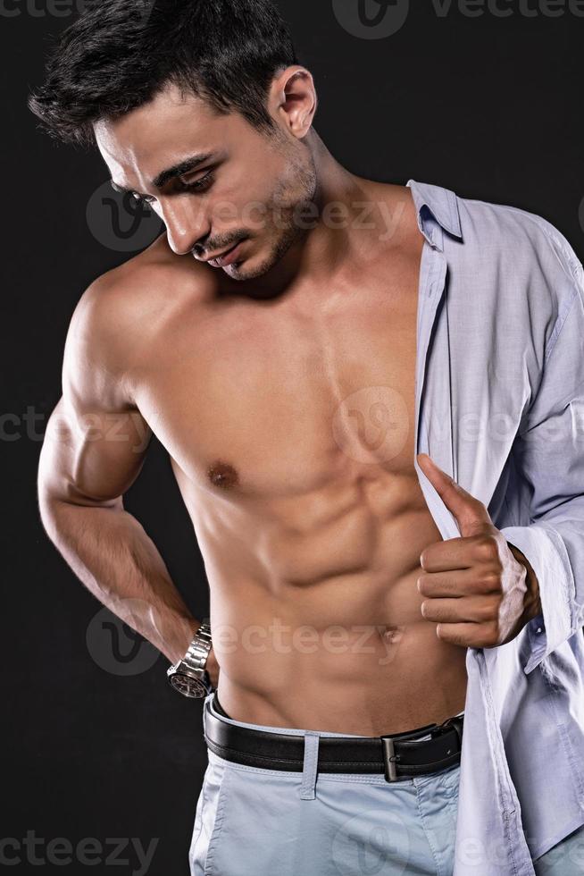 Handsome Arab male model with perfect body posing in studio. Portrait of a athletic male model posing on dark background in the studio. Fashion concept. photo