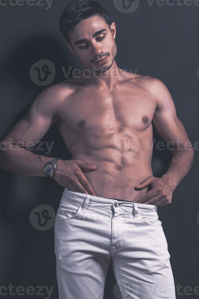 guapo modelo árabe masculino con cuerpo perfecto posando en el estudio. retrato de un modelo masculino atlético posando sobre fondo oscuro en el estudio. concepto de moda. foto