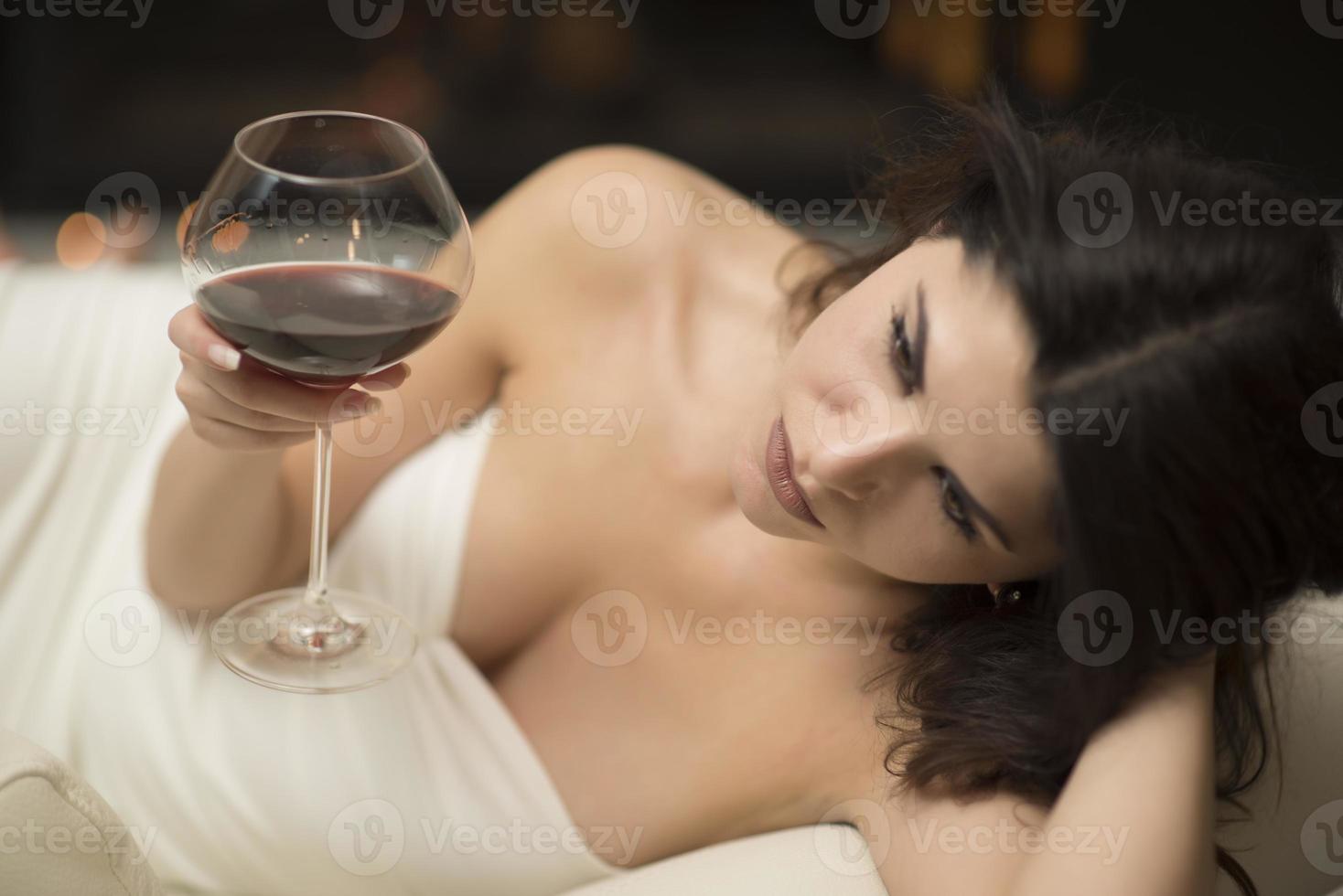 attractive brunette drinking wine by a fireplace photo