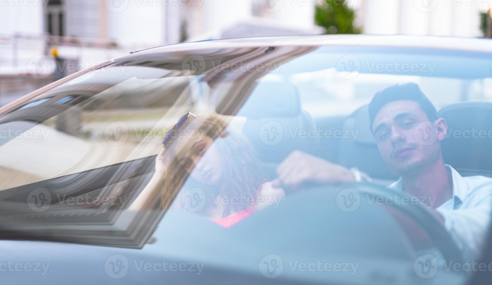 Happy young couple having fun in convertible car on beautiful summer day photo