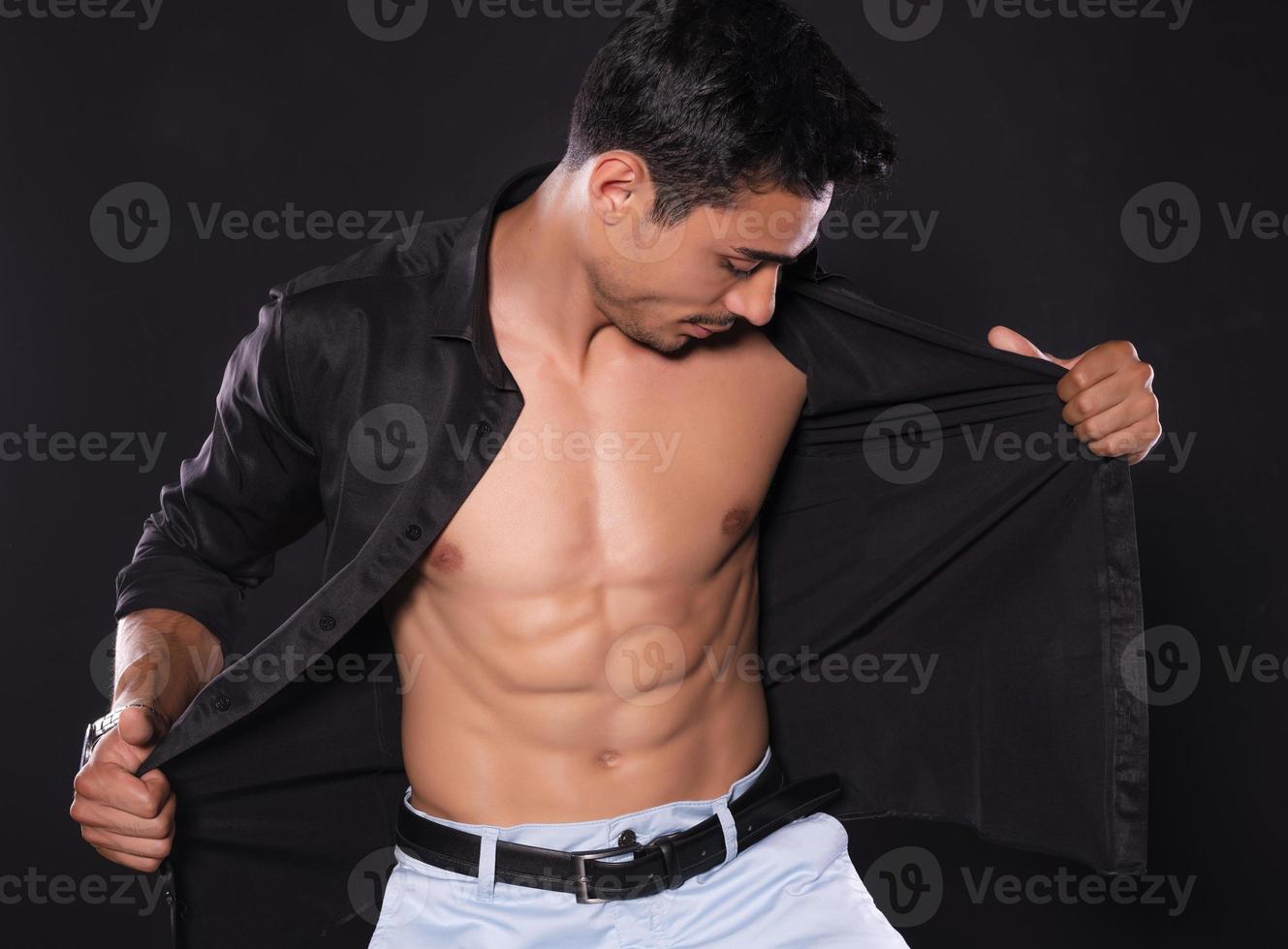 Handsome Arab male model with perfect body posing in studio. Portrait of a athletic male model posing on dark background in the studio. Fashion concept. photo