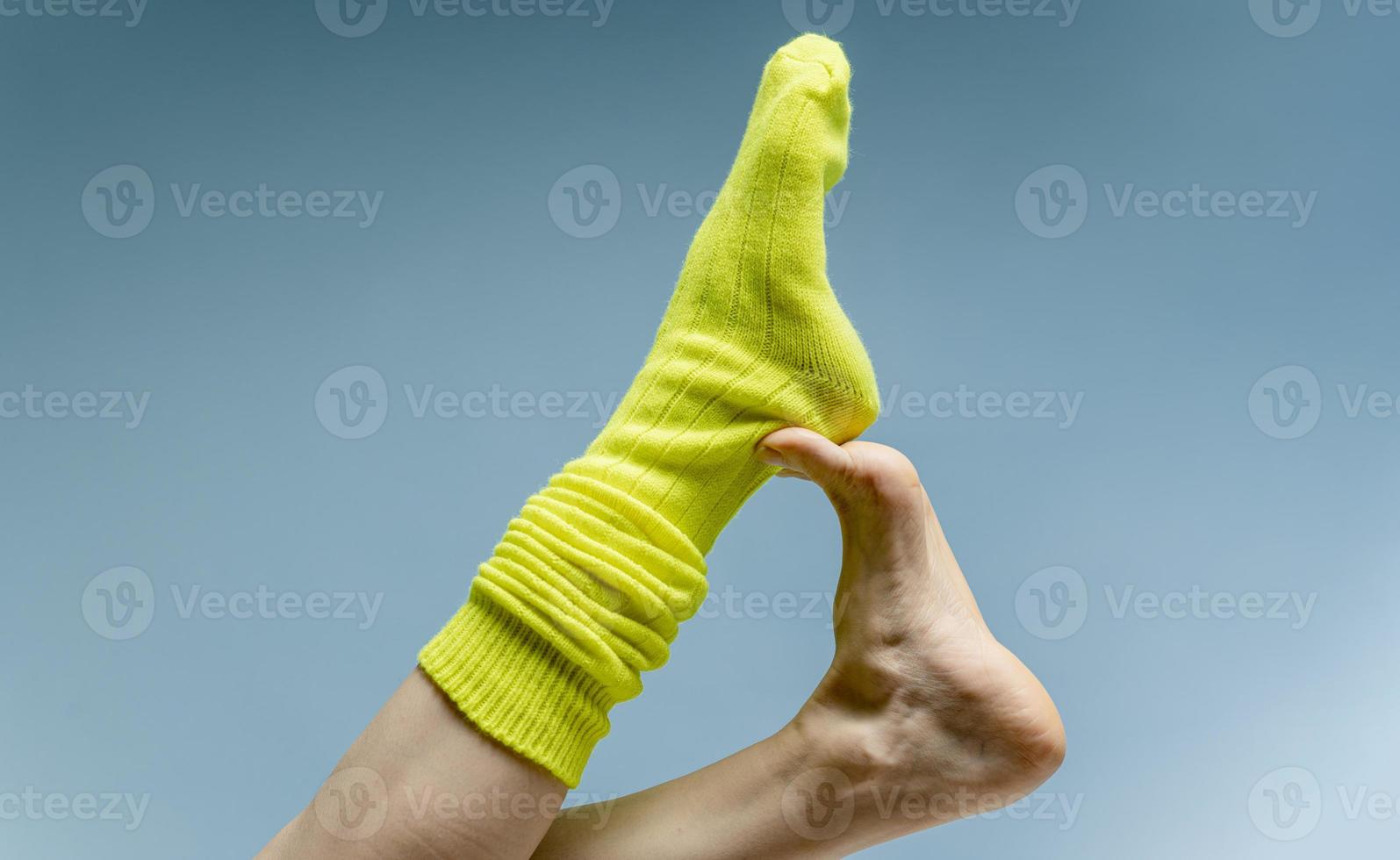 Woman with beautiful legs wears green socks on her feet. Isolated on blue background photo